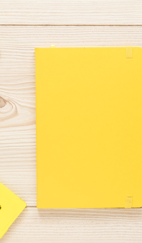 Желтый блокнот с ручкой и кассетами на столе