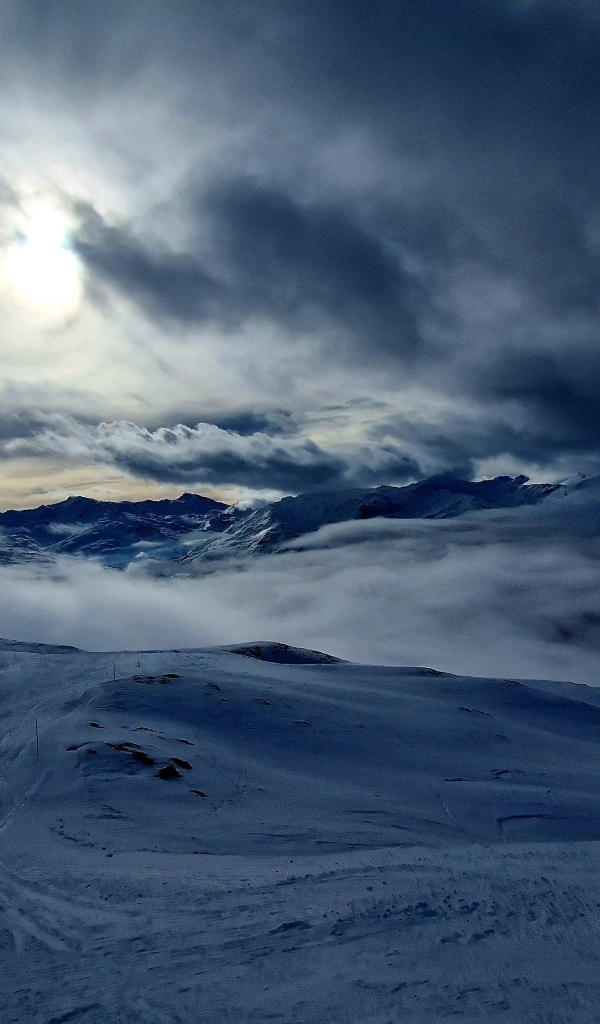 Луна в облачном небе над заснеженными горами