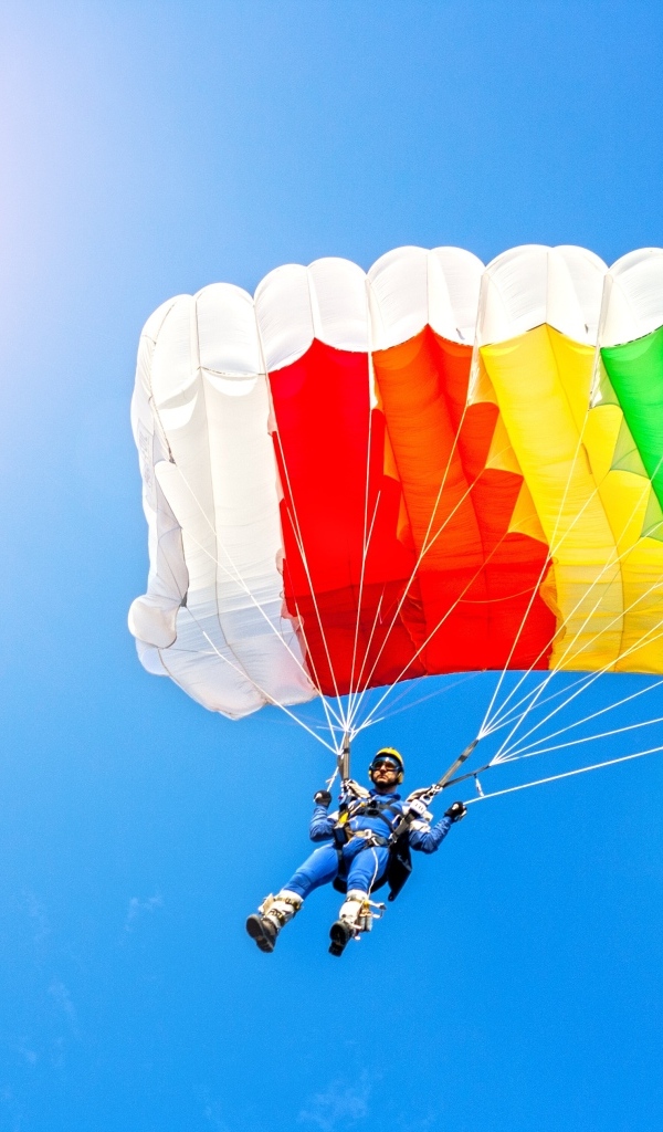 Парашютист в голубом небе в лучах солнца