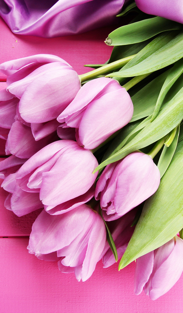 Красивый букет тюльпанов с лентой на розовом столе