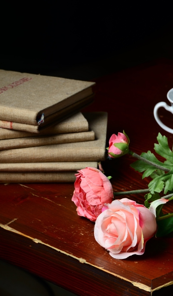 Книги на столе с цветами и чашкой