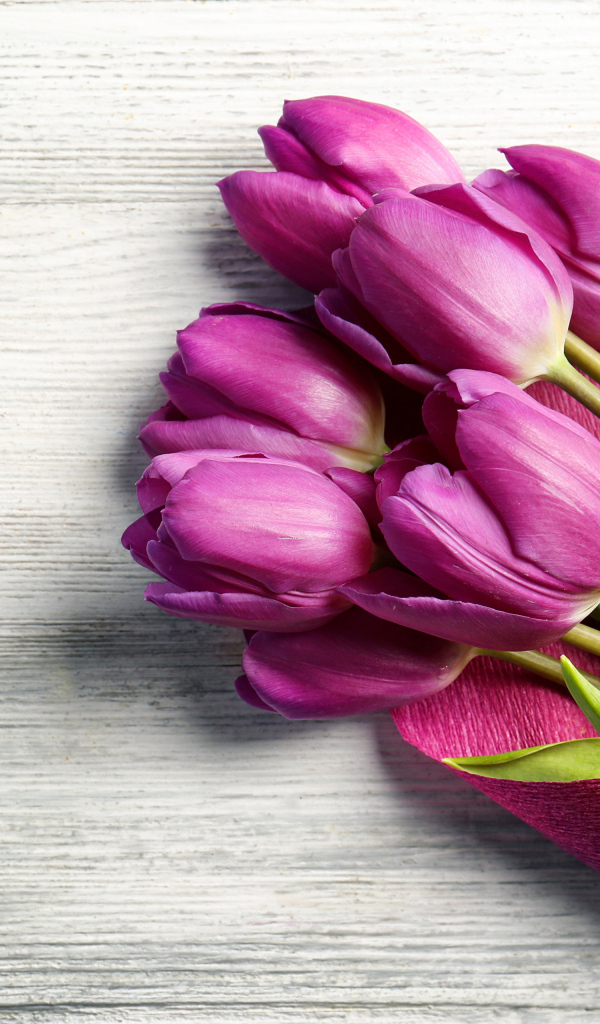 Букет сиреневых тюльпанов в бумаге на столе