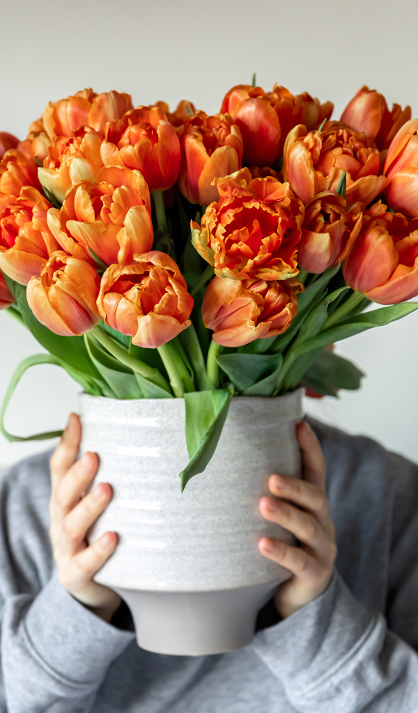 Букет оранжевых тюльпанов в вазе в руках