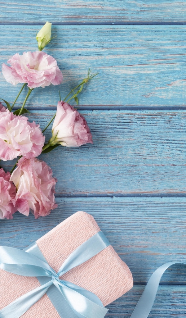 Букет розовой эустомы с подарком на голубом фоне