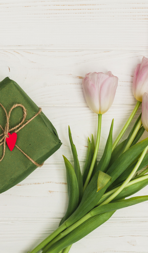 Букет розовых тюльпанов на столе с подарком