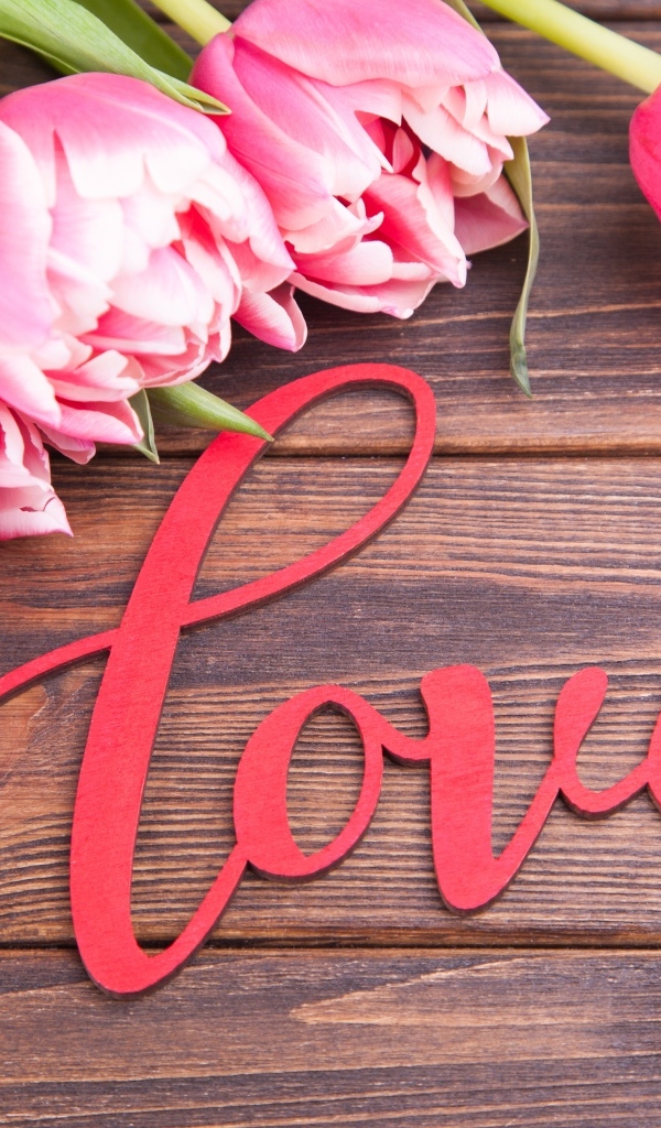 Букет розовых тюльпанов с надписью любовь на деревянном столе