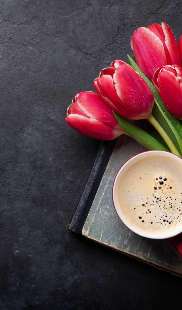 Букет красных тюльпанов с чашкой кофе на черном столе