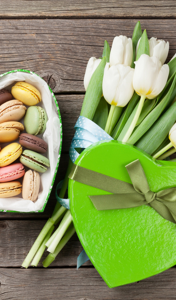 Букет белых тюльпанов на столе с коробкой печенья макарун