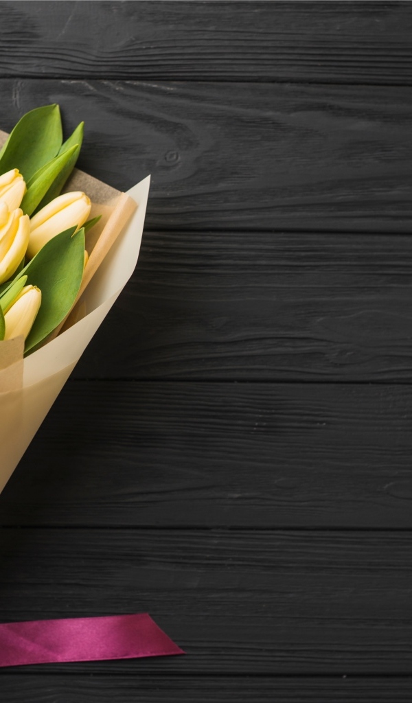 Букет желтых тюльпанов в бумажной упаковке с лентой