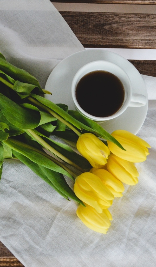 Букет желтых тюльпанов с чашкой кофе на лавке