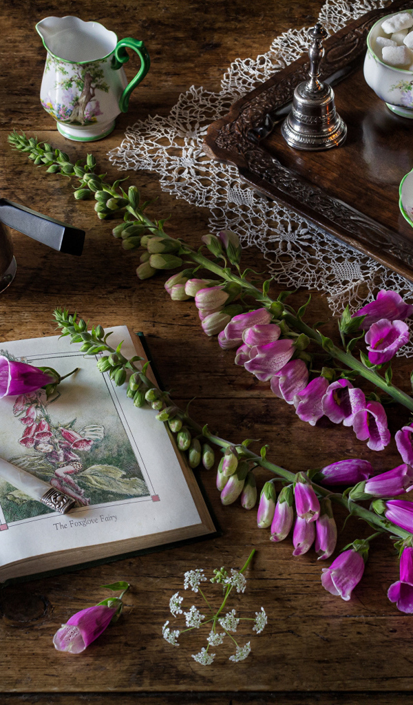 Розовые цветы на столе с книгой и чаем