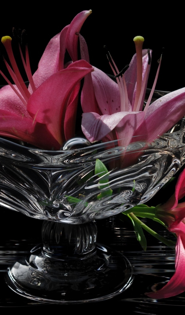 Розовые лилии в стеклянной вазе на столе