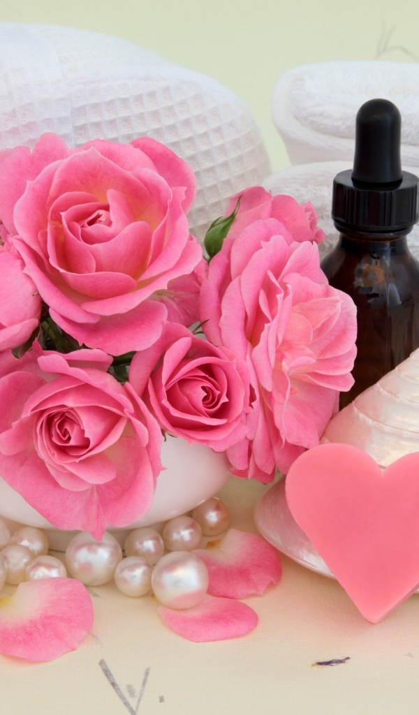 Розовые розы с полотенцами, ракушками и маслом на столе