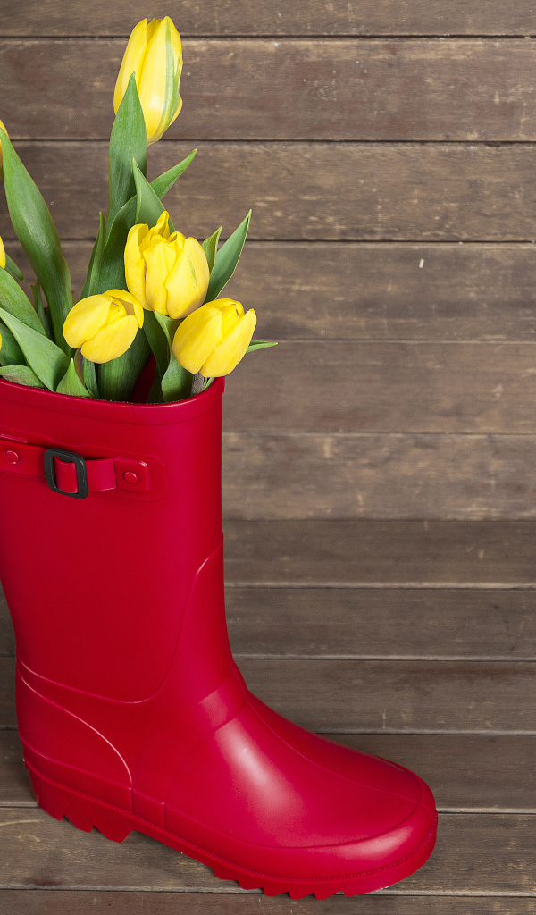 Красный сапог с желтыми тюльпанами на деревянном столе