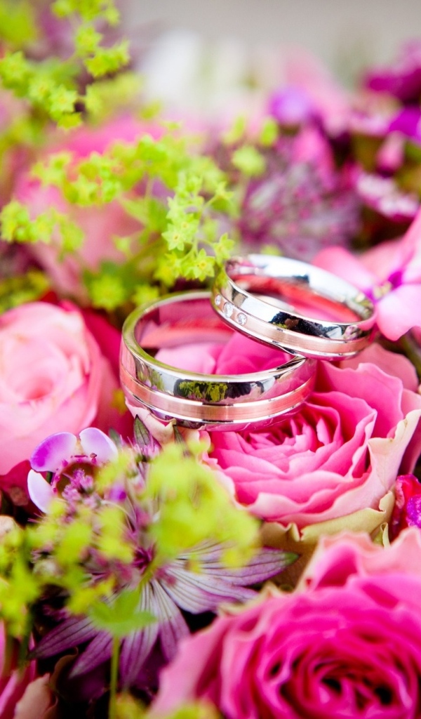 Два обручальных кольцо на букете розовых цветов
