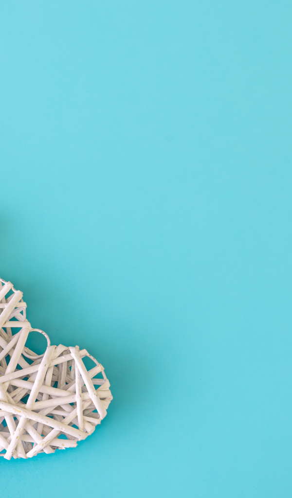 Белое плетеное сердце с букетом желтых тюльпанов на голубом фоне