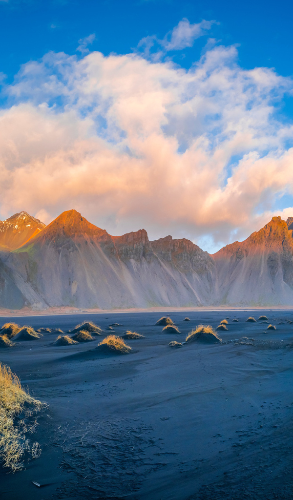 Облако в голубом небе над покрытой солнцем горой