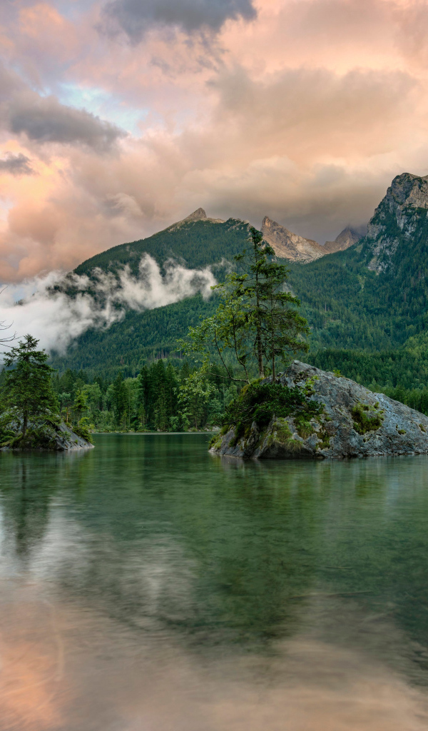 Покрытые зеленью горы в облаках у озера