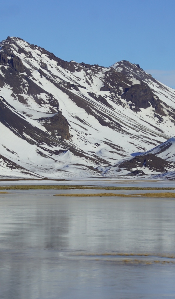 Горы в снегу под голубым небом у воды