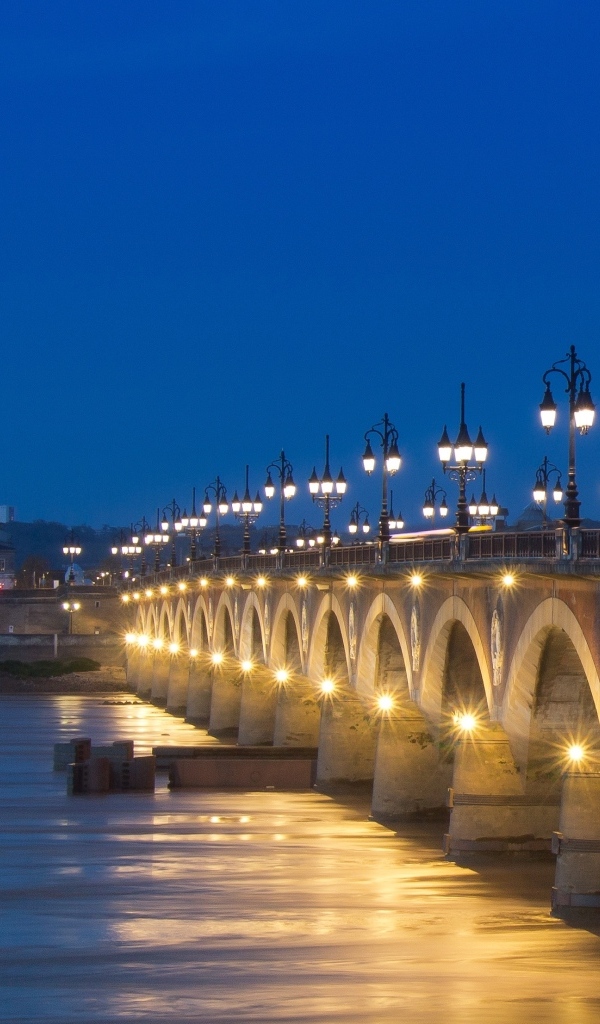 Красивый светящийся мост через реку ночью 