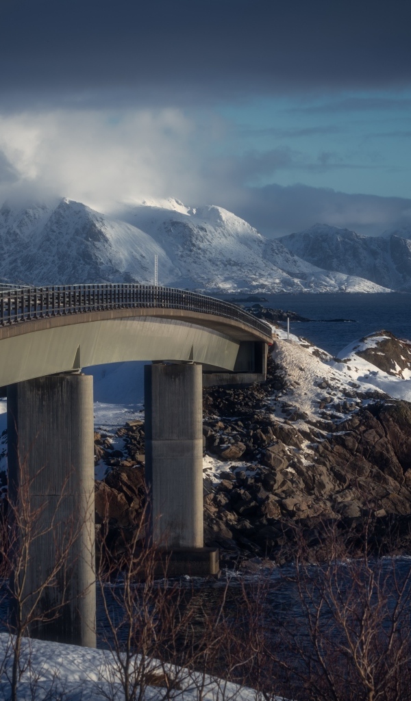 Мост через реку в заснеженных горах 