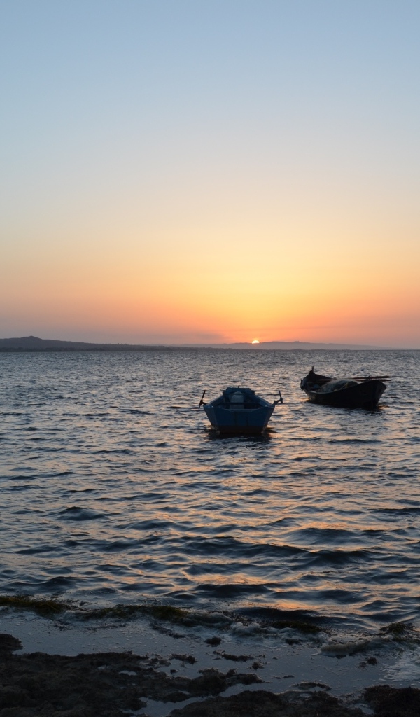 Лодки на морском побережье на закате