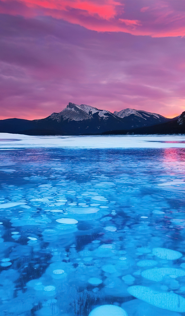 Красный закат солнца над горами у покрытого льдом озера