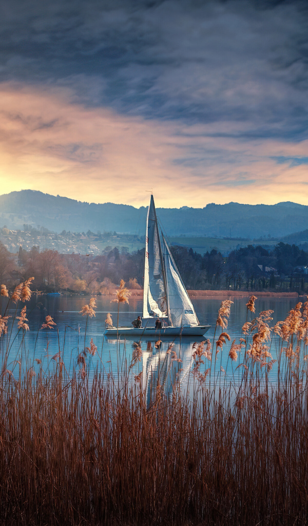 Парусная лодка на озере на закате солнца