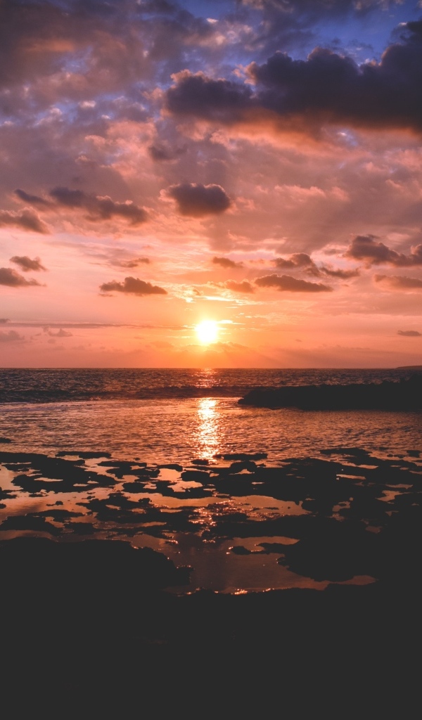 Закат яркого летнего солнца в небе над морем