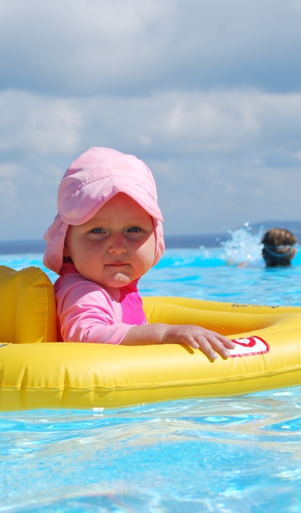 Ребенок со спасательным кругом плавает в бассейне