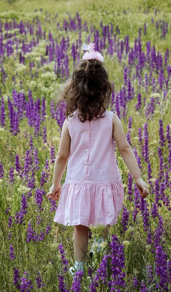 Девочка в розовом платье гуляет по полю с цветами