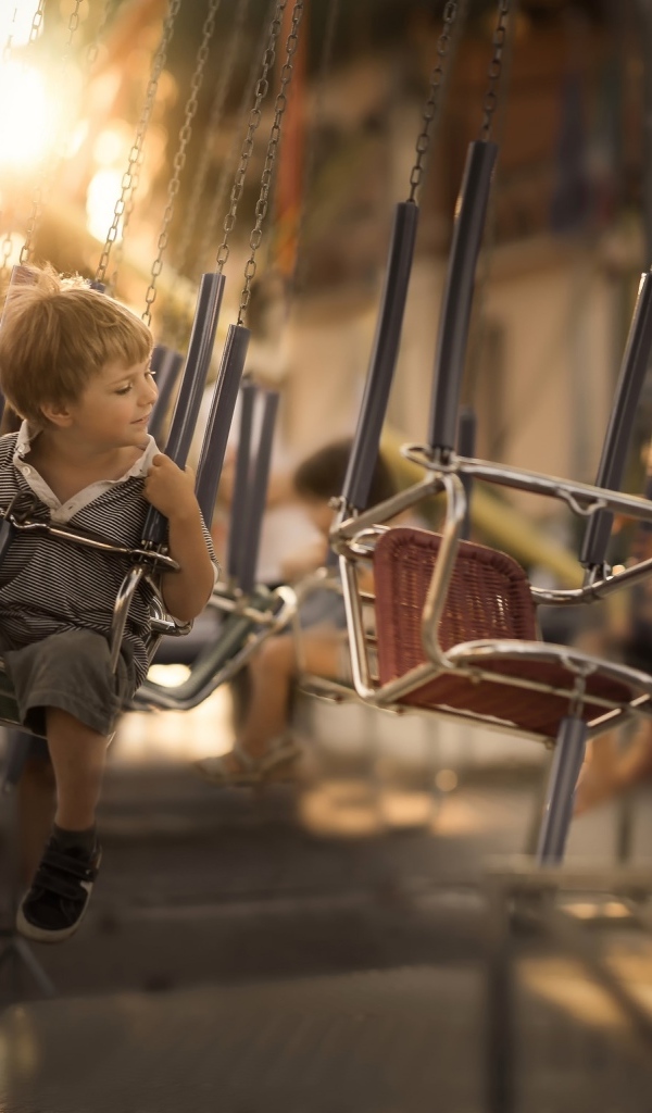 Маленький мальчик катается на каруселях