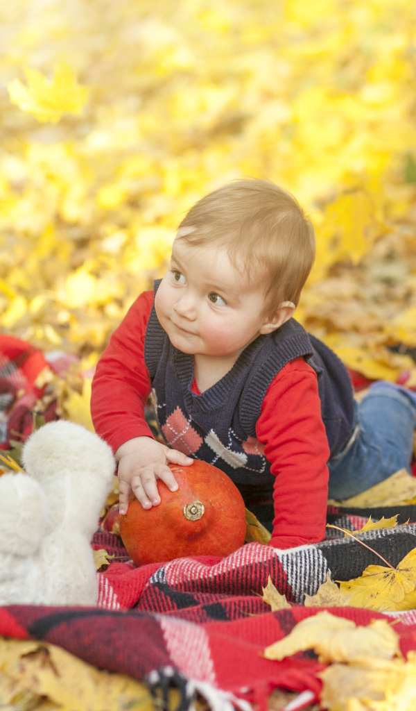 Маленький ребенок лежит на покрывале на земле осенью