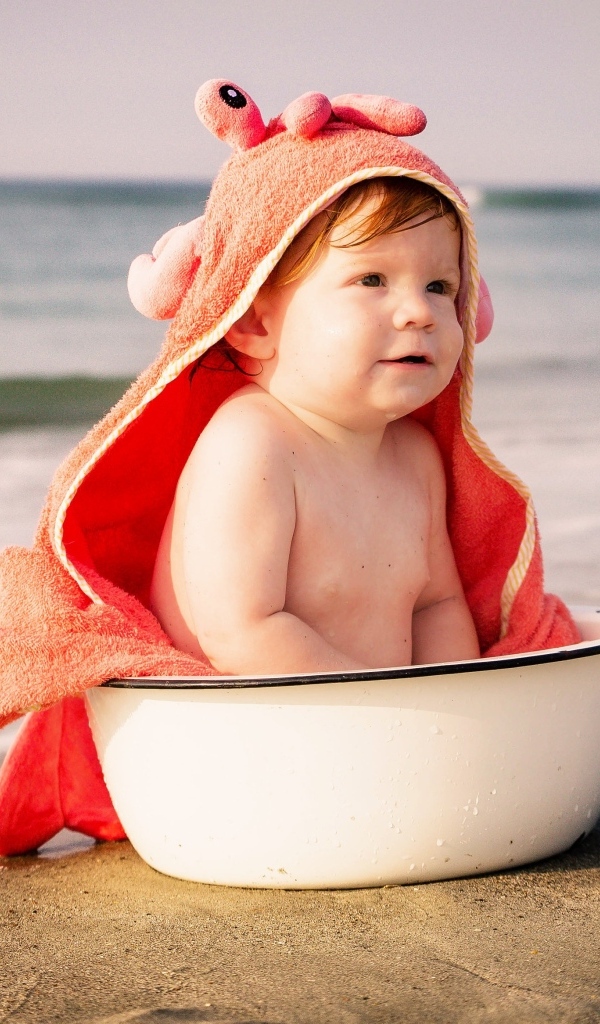 Ребенок в миске на берегу моря