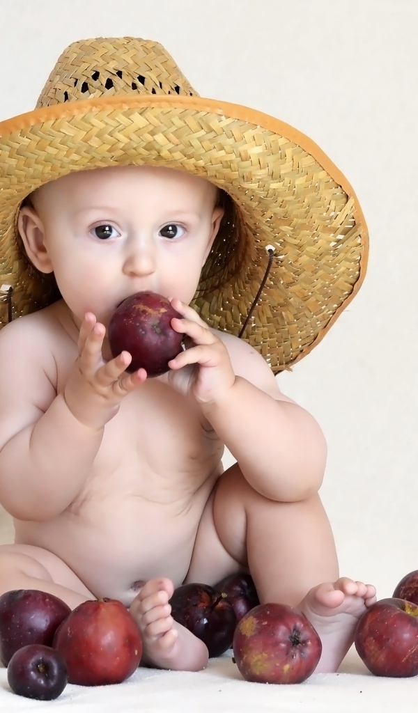 Малыш в шляпе грызет яблоки