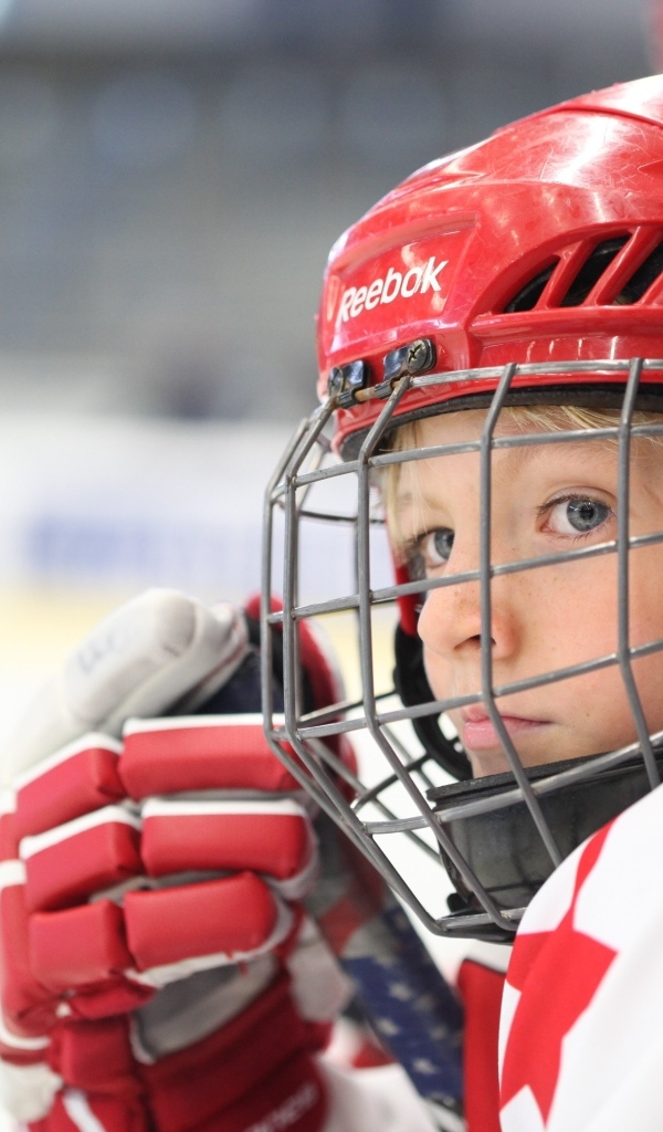 Мальчик в красном шлеме хоккеиста на поле