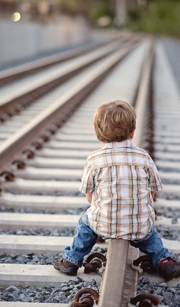 Мальчик сидит на железнодорожных рельсах