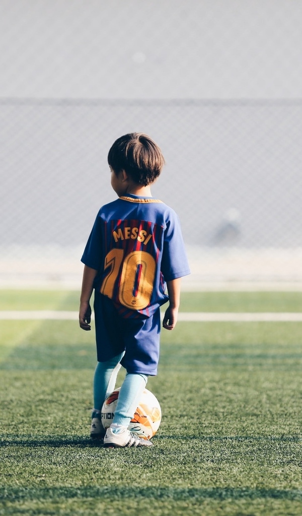 Мальчик футболист с мячом на поле