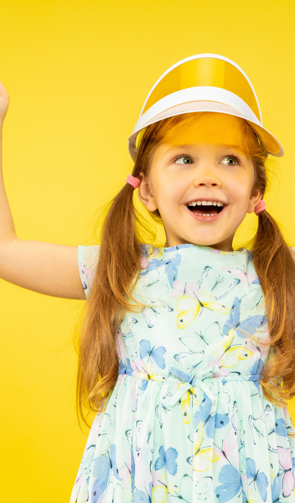 Веселая девочка в платье на желтом фоне