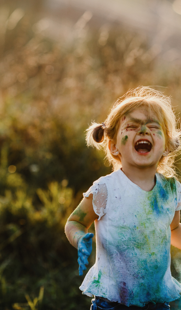Веселая девочка в краске на улице