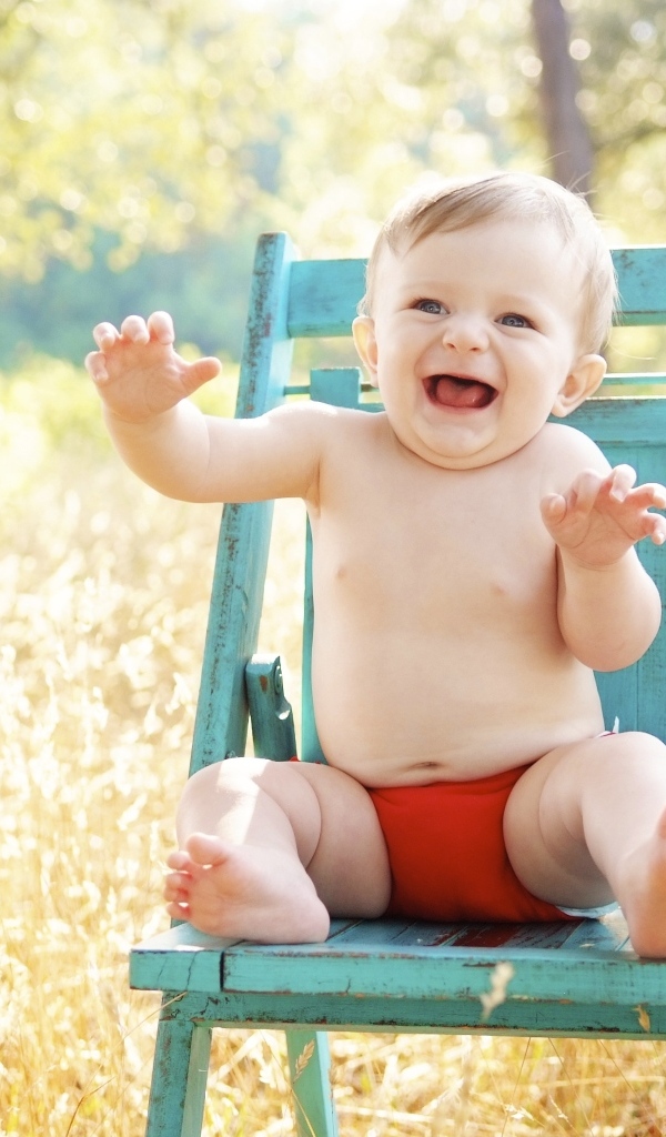 Веселый маленький мальчик в кресле 