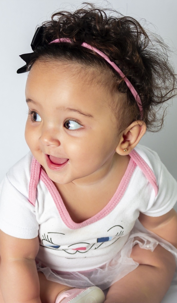 Веселая маленькая девочка с ободком на голове