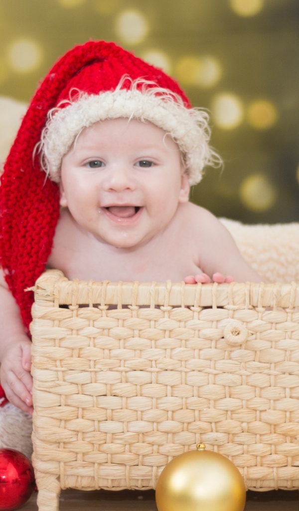Ребенок в корзине в новогодней шапке с игрушками