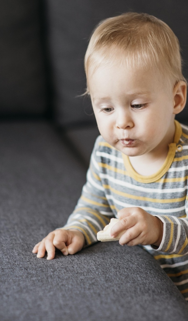 Любопытный маленький ребенок у дивана