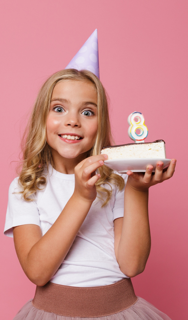 Милая девочка отмечает день рождения на розовом фоне