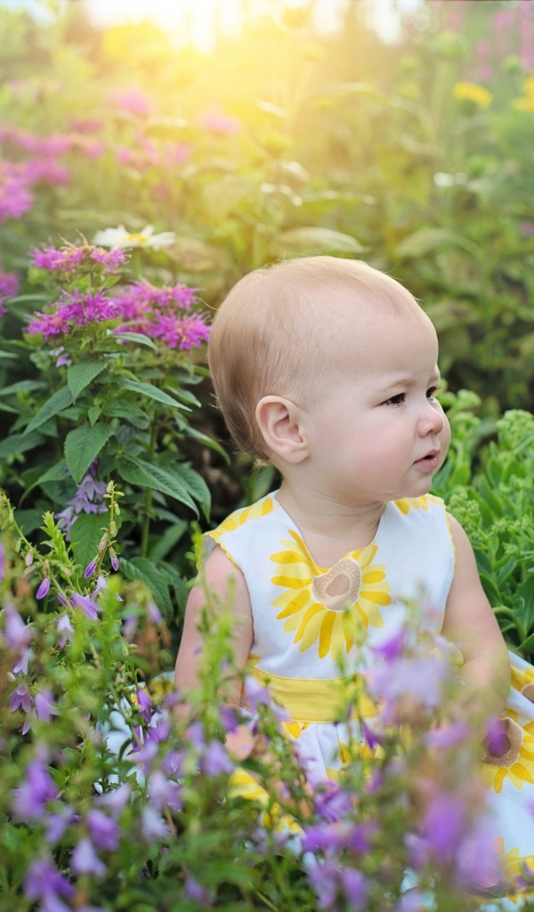 Милая девочка в платье сидит в цветах