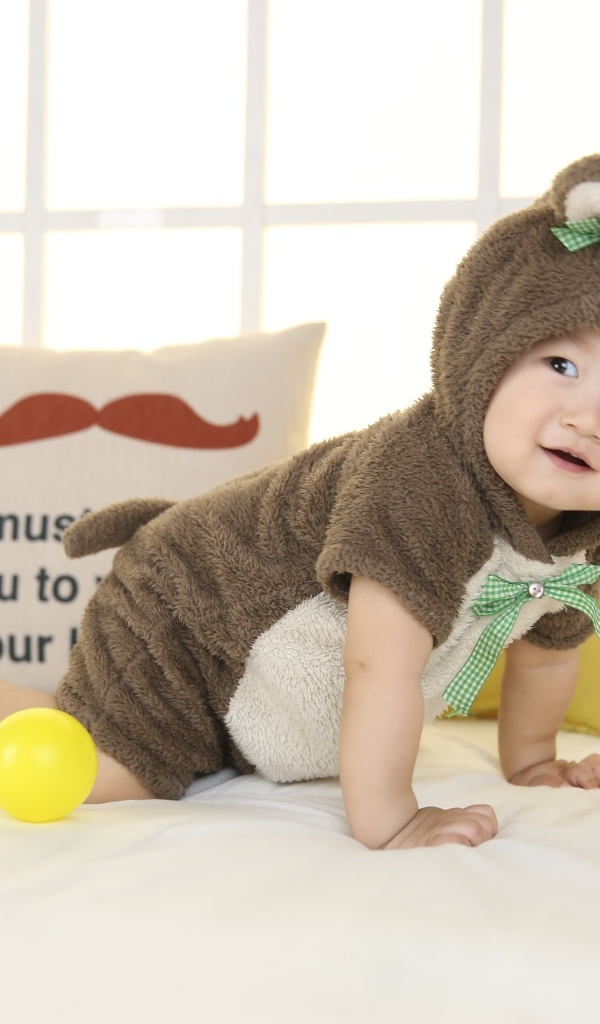 Смешной ребенок азиат в костюме на кровати