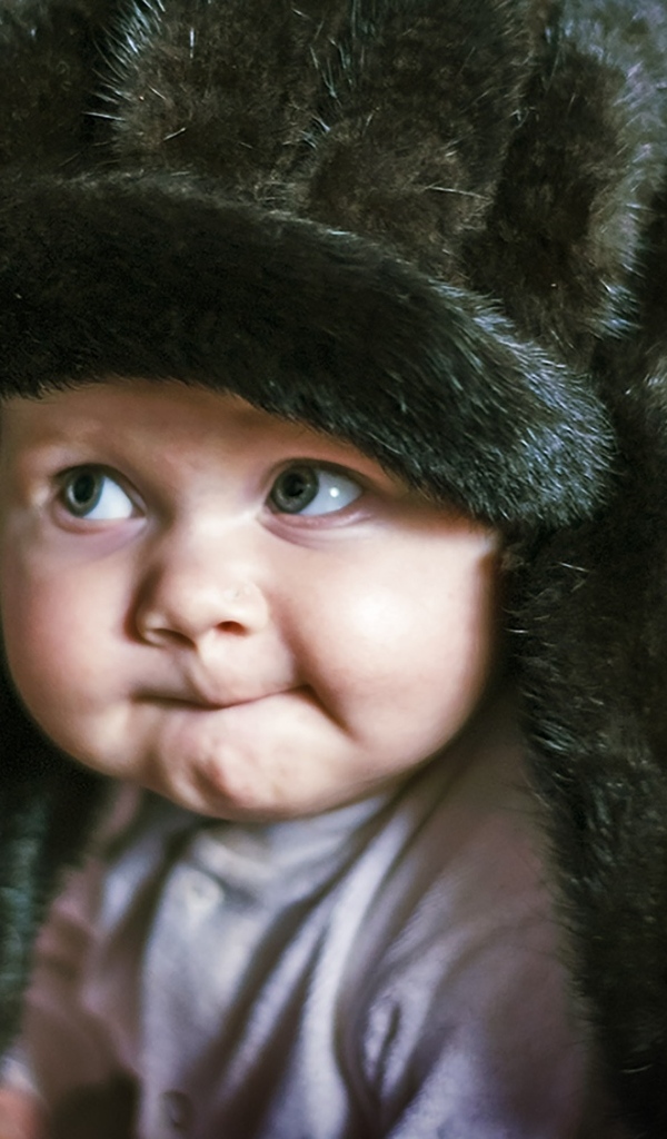 Смешной ребенок в черной меховой шапке