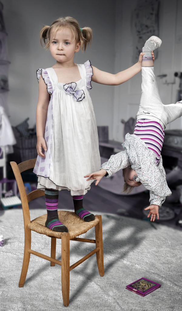 Девочка держит маленького брата за ногу