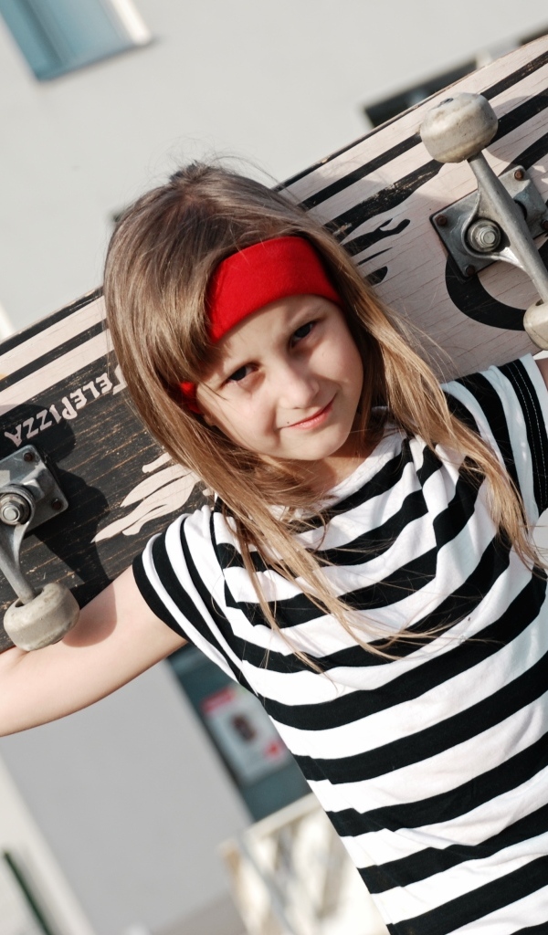 Девочка в полосатом платье со скейтбордом в руках